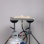 High pressure adjustable regulator installed on a propane tank and burner pan, on a low flame height
