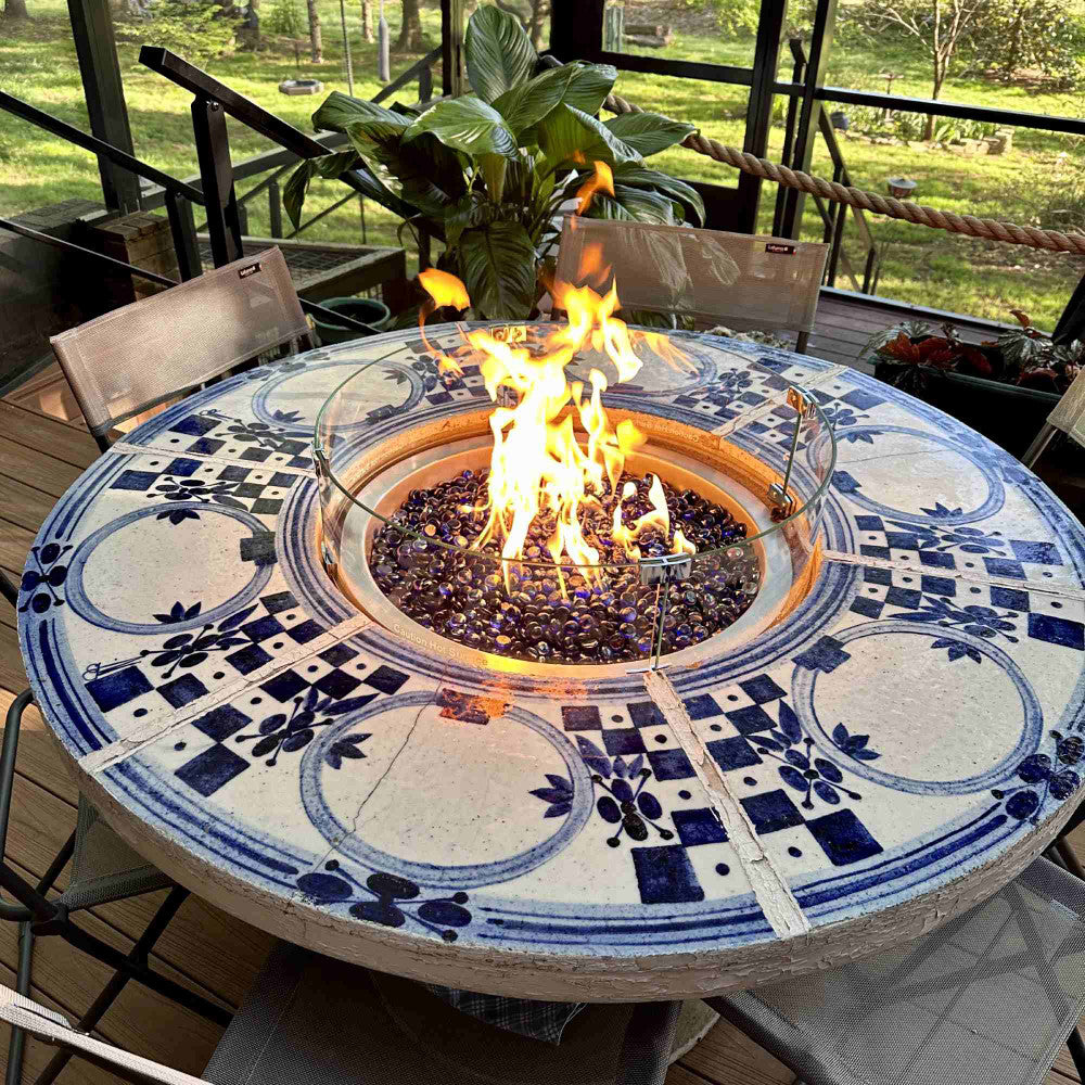 Fire pit table with a burner and wind guard placed in the porcelain tabletop