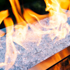 Medium view of flames dancing across a crystalline bed of clear tempered fire glass