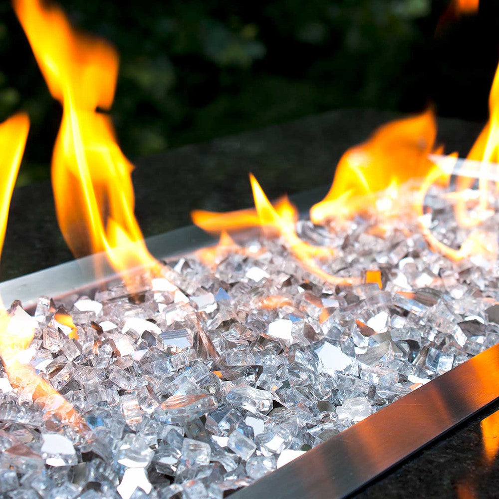 Medium shot of shiny silver fire glass in a lit fire pit