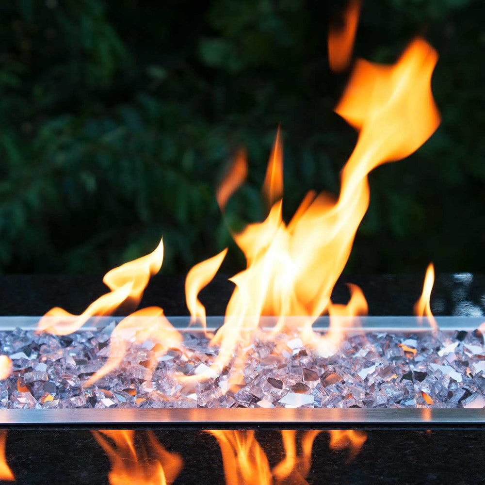 Horizontal image of large flames ablaze on top of diamond starlight fire glass in a fire pit
