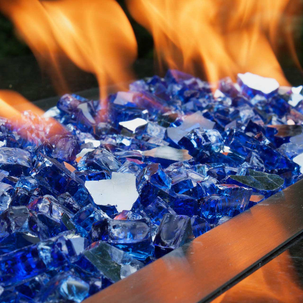 Medium shot of a sea of sapphire blue tempered fire glass in a blazing fire pit